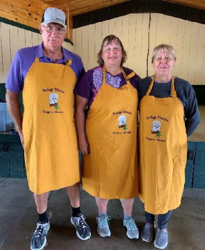 Three people wearing cooking aprons. 